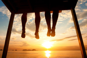 silhouette of a couples legs resting over the edge of a dock at sunset